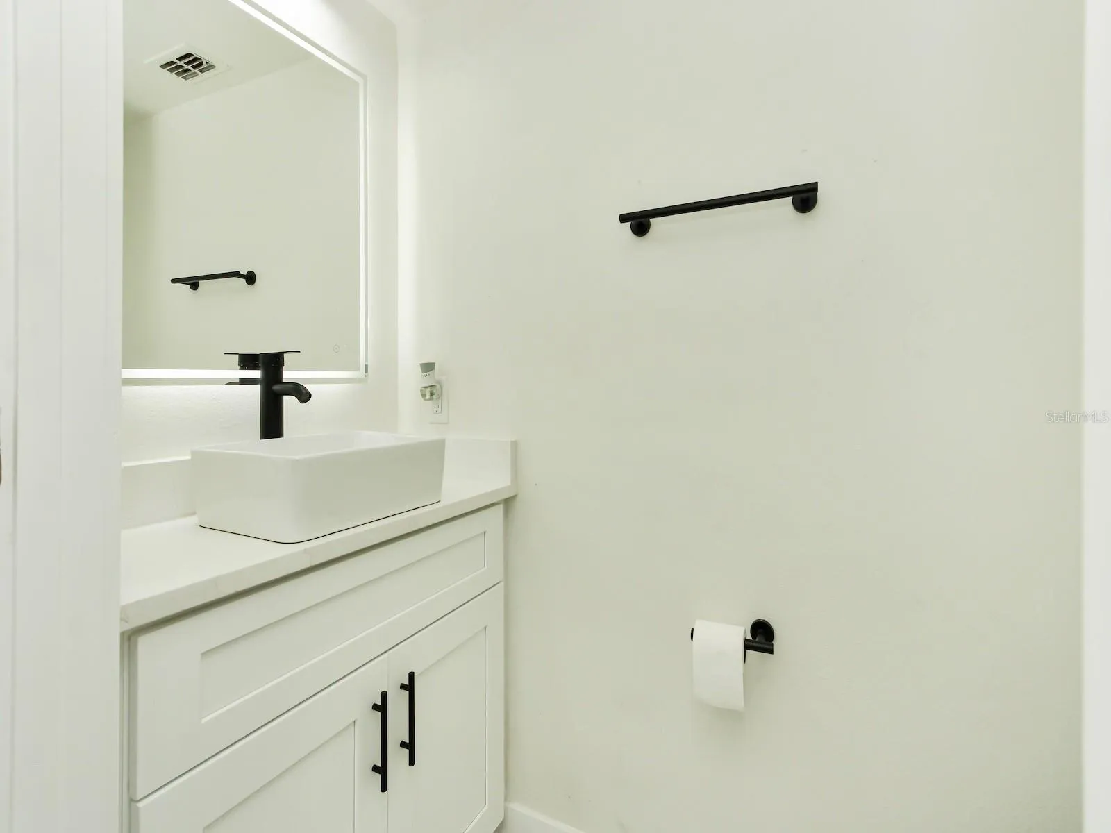 Half bathroom completely renovated with Quartz countertops, sink, light fixtures, toilet, and water features.