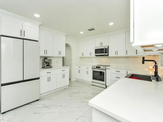 the kitchen counter tops are quartz with a quartz backsplash and soft closed cabinets that are dressed with crown molding and on top and bottom of the cabinets.