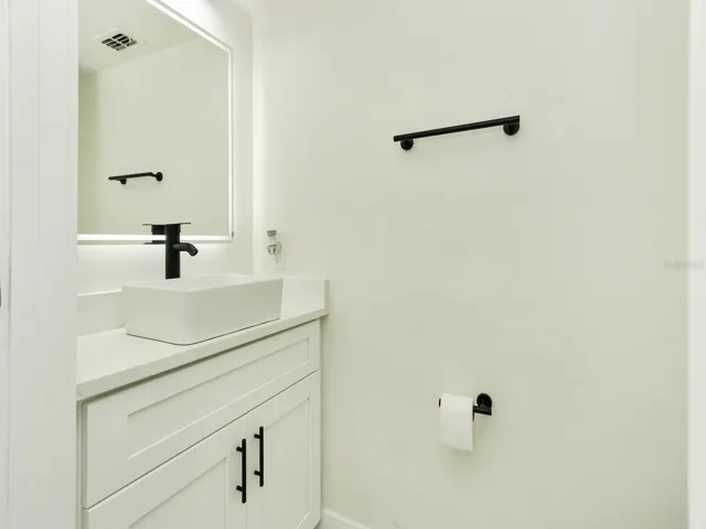 Half bathroom completely renovated with Quartz countertops, sink, light fixtures, toilet, and water features.