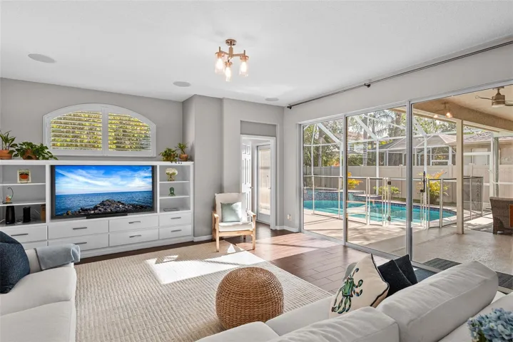 Casual TV room with half bath and sliding doors overlooking the pool and patio.