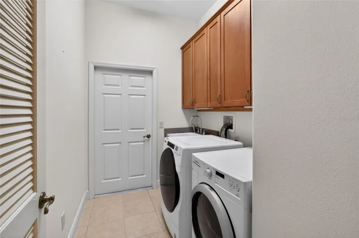 LAUNDRY ROOM WITH FRONT LOAD WASHER AND DRYER THAT DO CONVEY WITH THE HOME AND A BUILT-IN SINK AND MORE CABINET SPACE.
