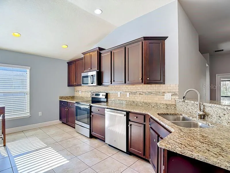Beautifully updated kitchen featuring rich espresso cabinetry, granite countertops, and a coordinating tile backsplacsh.