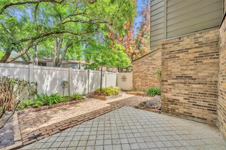 Private brick patio with fence opening to green space