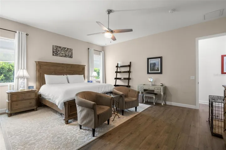 The spacious primary suite offers generous proportions, wide-plank luxury vinyl flooring, abundant natural light, neutral finishes, and a contemporary ceiling fan. Large enough to accommodate a sitting area, the private retreat also features direct access to the ensuite bath and oversized walk-in closet.
