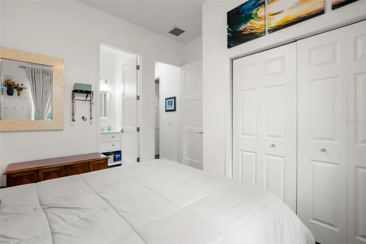 Bedroom 3 features wide-plank luxury vinyl flooring, abundant natural light, neutral finishes, a contemporary ceiling fan, and built-in shelving for additional display and storage space. The room also includes oversized paneled doors and convenient access to the ensuite full bath.