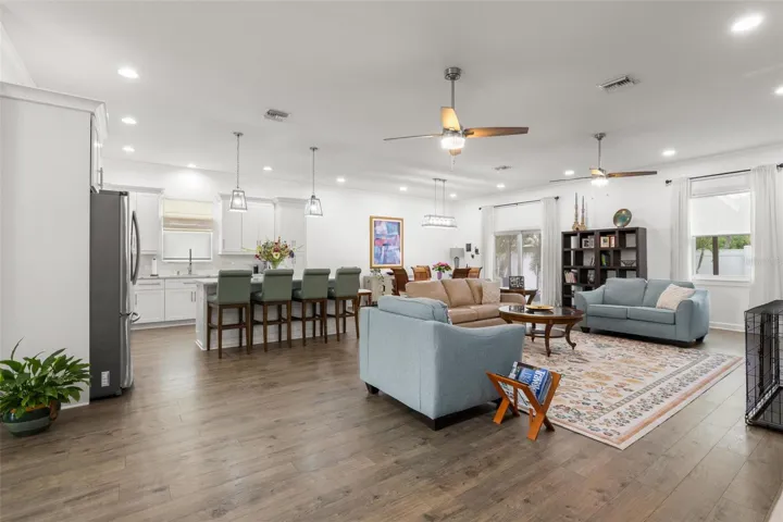 The expansive open-concept layout features wide-plank luxury vinyl flooring, recessed lighting, crown molding, and seamless flow between the great room, dining area, and chef-inspired kitchen. High ceilings and abundant natural light enhance the airy feel, while oversized impact windows and sliding glass doors bring the outdoors in.