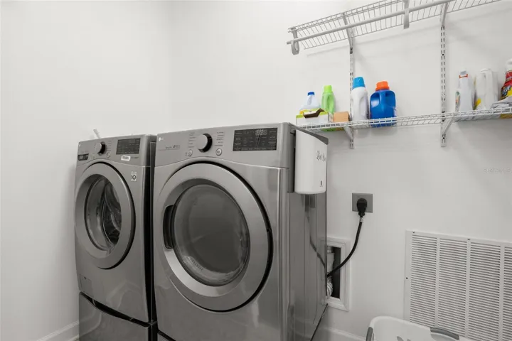 The interior laundry room includes built-in wire shelving for additional organization, side drying racks, and storage space.
