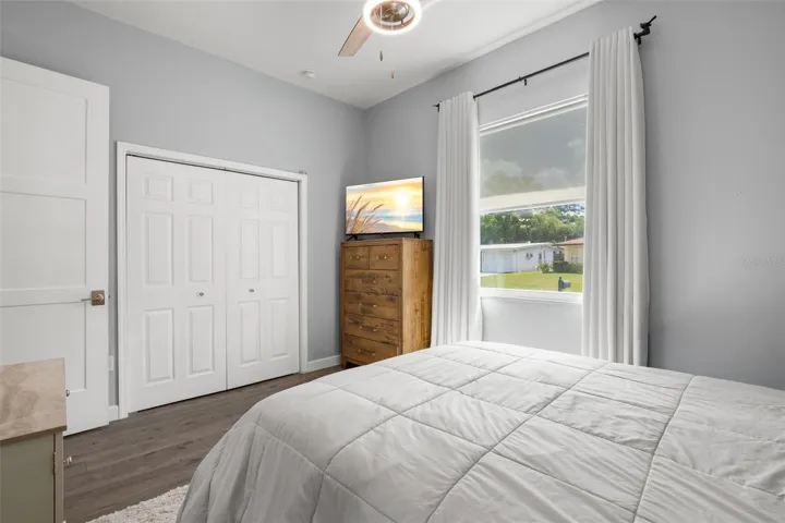 Bedroom 2 features wide-plank luxury vinyl flooring, a built-in closet, a contemporary ceiling fan, and abundant natural light.