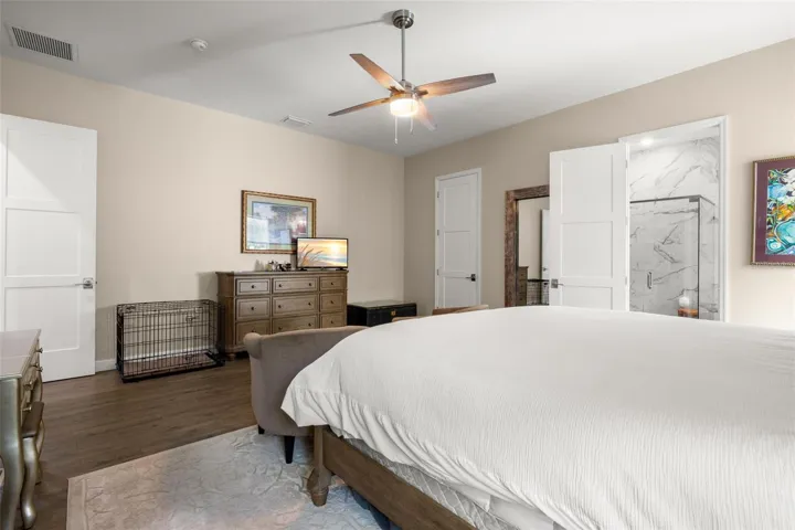 The generously sized primary suite offers a spacious layout with wide-plank luxury vinyl flooring, neutral finishes, oversized paneled doors, and a contemporary ceiling fan. The private ensuite bath features designer tile finishes, while the oversized walk-in closet provides substantial storage space.
