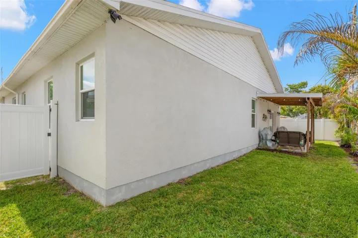 The fully fenced backyard offers privacy, low-maintenance landscaping, and ample green space surrounding the covered rear patio. Rain gutters, impact windows, and durable block construction contribute to the home’s thoughtful exterior design and functionality.