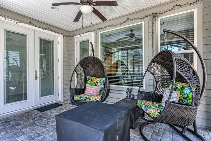 Covered Rear patio with ceiling fan and doors to primary AND living room