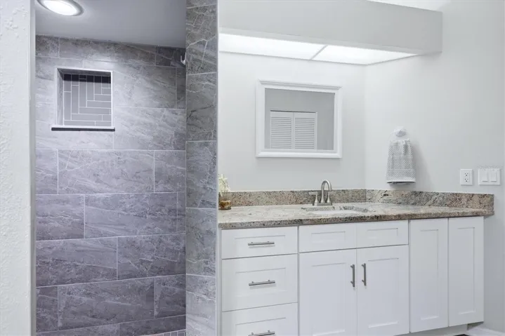 PRIMARY EN-SUITE BATHROOM WITH SKYLIGHT, DUAL CLOSETS WALKIN AND BUILT IN, TALL VANITEIS AND GRANITE COUNTER TOP, WLAK IN SHOWER WITH HERRINGBONE TILE SHOWER FLOOR AND NICHE