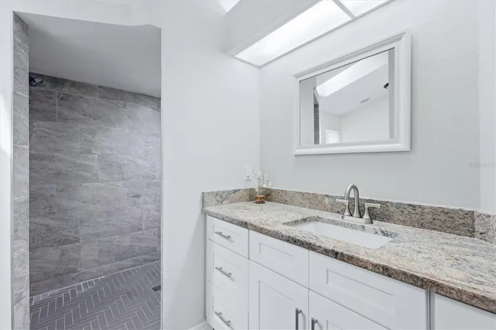 PRIMARY EN-SUITE BATHROOM WITH SKYLIGHT, DUAL CLOSETS WALKIN AND BUILT IN, TALL VANITEIS AND GRANITE COUNTER TOP, WLAK IN SHOWER WITH HERRINGBONE TILE SHOWER FLOOR AND NICHE