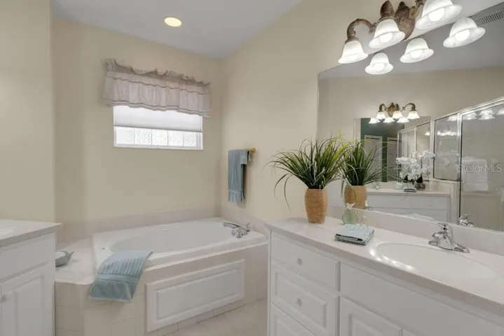 The ensuite bathroom features a deep soaking tub, dual vanities and . . .