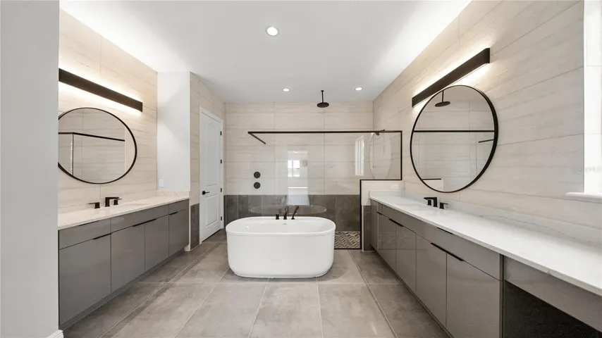 Spa-inspired primary bath with dual vanities, freestanding tub, and oversized shower.