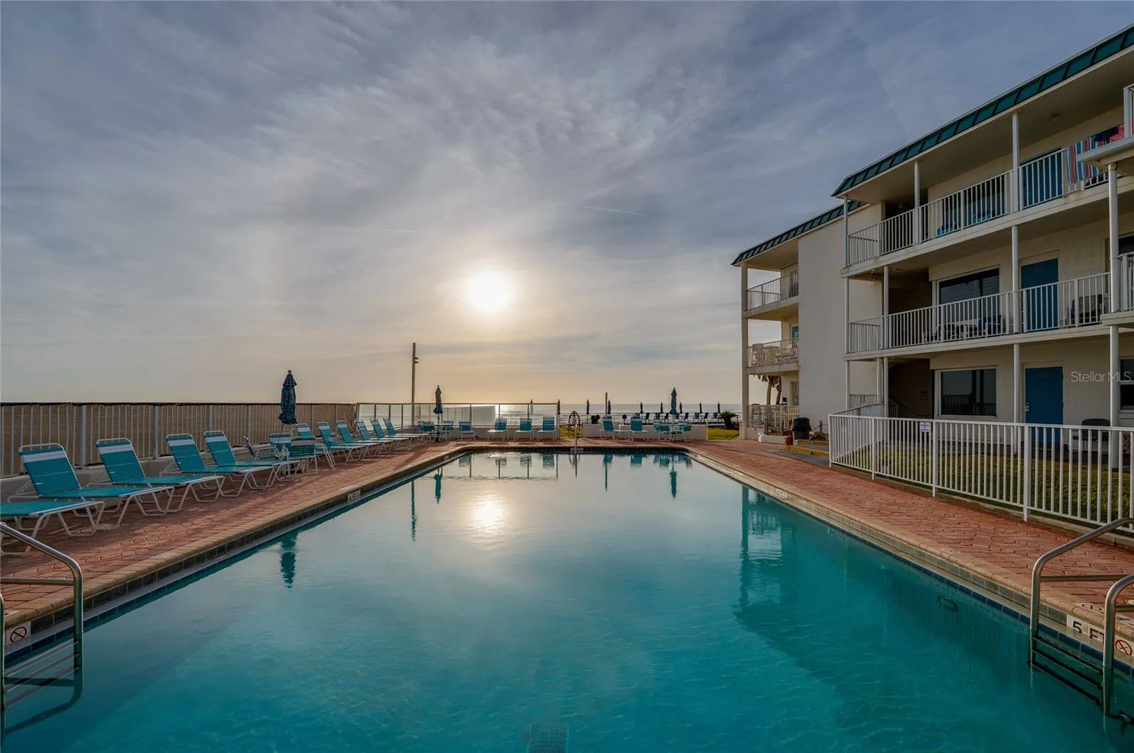 Pristine pool area featuring built-in stairs for easy entry and a dedicated lift for accessibility, all set against the backdrop of the rolling waves and blue skies.