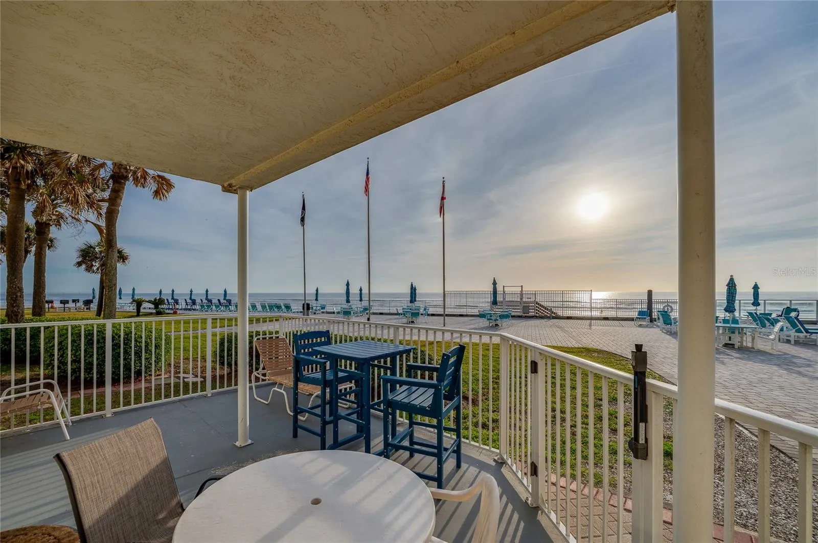 Spacious covered patio featuring versatile seating options, including a high-top bistro set and lounge chair.
