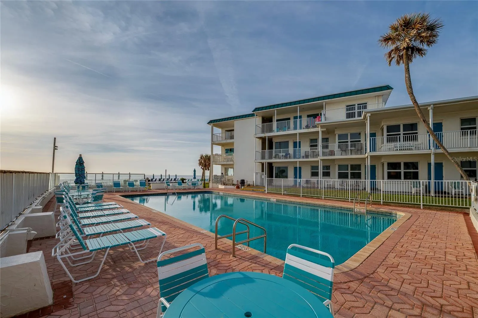 Large, crystal-clear swimming pool surrounded by a spacious sun deck with premium lounge chairs. The ocean breeze and panoramic views create a true vacation atmosphere.