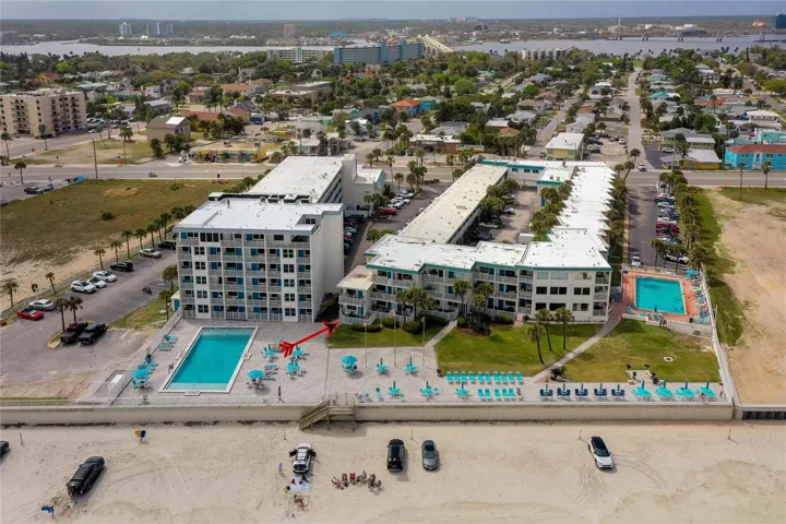 Expansive aerial of the oceanfront community featuring two pools, sun deck areas, and direct access to the beach. The layout is ideal for enjoying a relaxed coastal lifestyle.