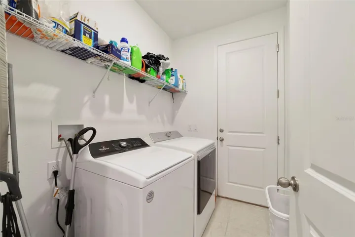 A DEDICATED LAUNDRY ROOM with washer, dryer, and storage shelving adds convenience and organization to everyday living.