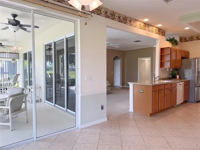 View of Dinette in Kitchen with sliders onto covered and screened in lanai, Living Room in background