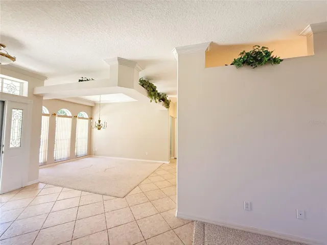View of Dining room, front door from Living room, decorative shelf, crown molding, beveled glass front door