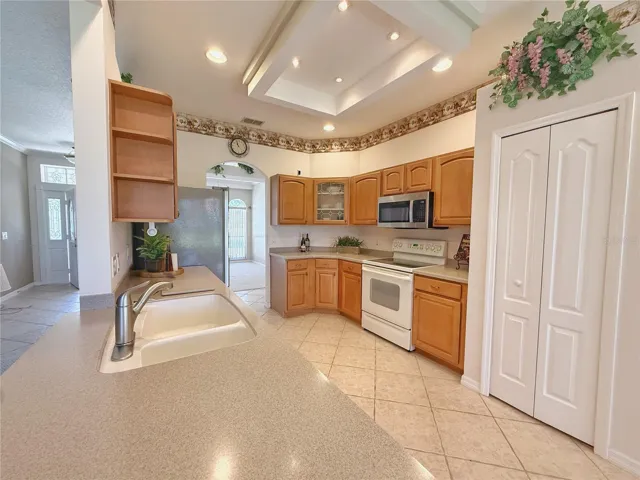 View of Kitchen with Dining room and Front entry in background, ceramic tile flooring, closet pantry, Corian countertops, recessed lighting
