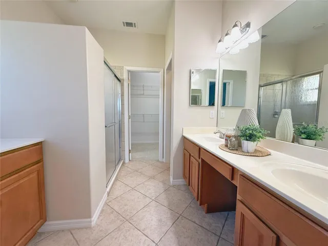 Additional view of Primary bathroom dual sink’s, Corian countertops, ceramic tile flooring, shower, water closet, walk in closet
