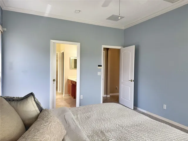 Primary bedroom with view of en suite bathroom with crown molding, walk in closet and sliding glass doors onto lanai with Golf course view