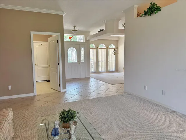 View of Dining Room from Living room, with laundry room visible, crown molding, decorative shelf, beveled glass front door