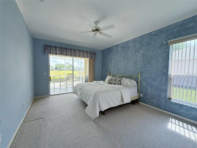 Primary Bedroom with sliding glass doors onto the covered and screened in lanai, crown molding, en suite bathroom, walk in closet