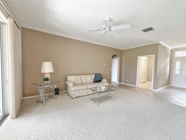 Living room with stackable sliding glass doors onto the covered and screened in lanai with Golf course view