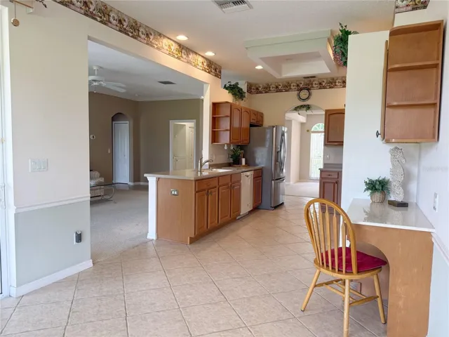 Kitchen view from Dinette with built in desk, ceramic tile flooring, solid wood cabinets, recessed lighting, view of Dining and Living room in background