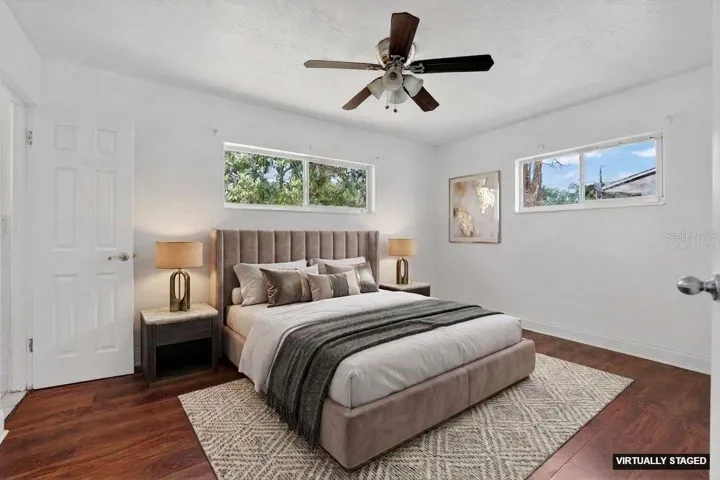 Virtually staged. Primary bedroom with laminate flooring, ceiling fan, and natural light