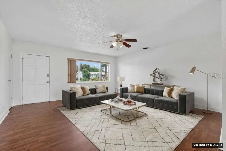 Virtually staged. Bright and open living room with wood laminate flooring and natural light throughout