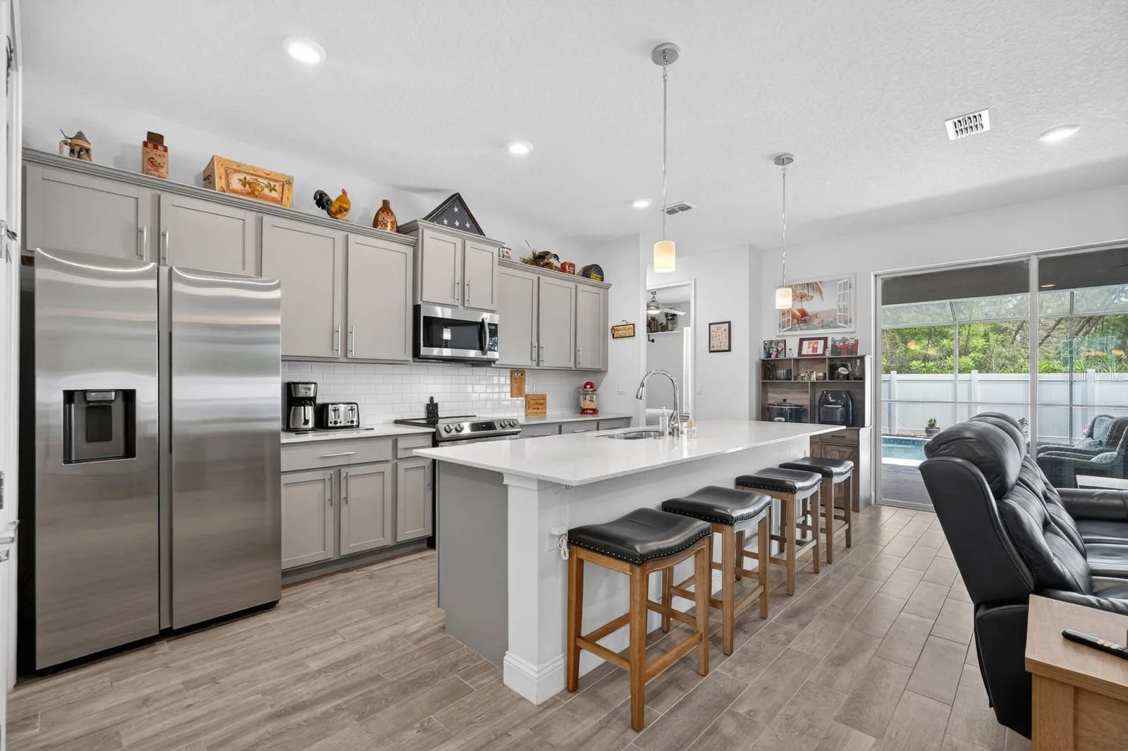 Kitchen features large island, quartz counters, backsplash and stainless steel appliances as well as a closet pantry