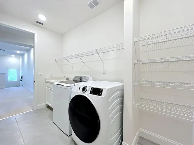 Well-equipped laundry room featuring utility sink, linen storage area, and all appliances included.