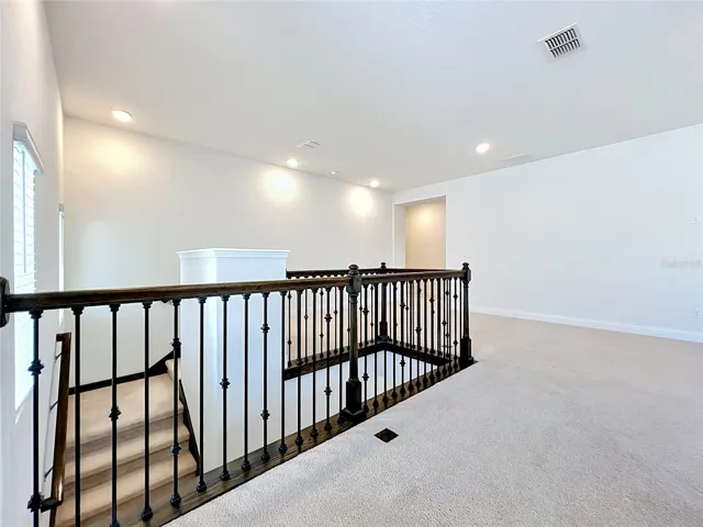 The staircase showcases decorative iron railing with rich stained oak handrails