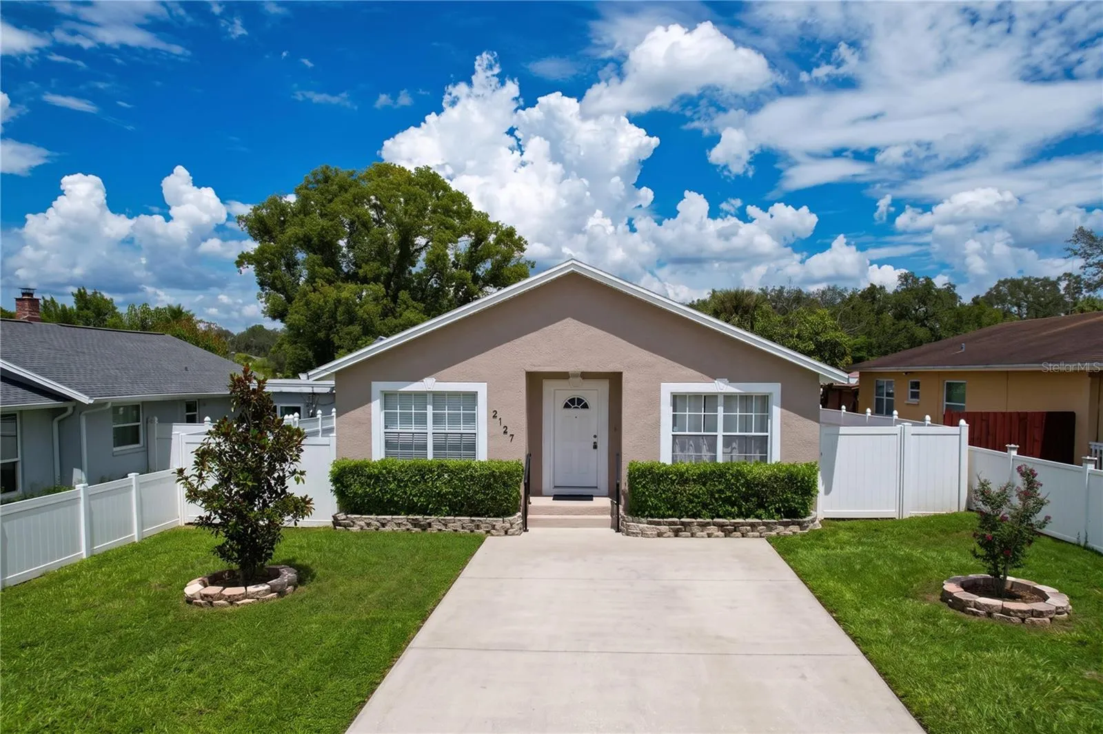 Full View of 3 Bedroom House Highlighting Landscaping. Attached White Fence On Right Side is an Entryway to One Bedroom Guest House Not Seen.