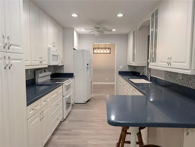 View of kitchen into dining room. Family room to right. Stunning kitchen features elongated counterspace, luxury vinyl flooring (2023), white 42