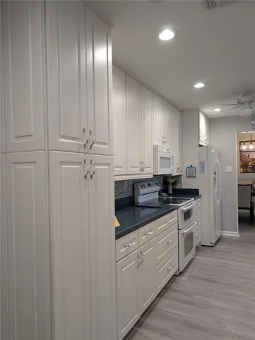 New kitchen design provides extra countertop workspace and additional cabinets for extra storage. White appliances include Maytag double oven, glass top range and new GE microwave hood (2020). GE side by side refrigerator features in door water/ice dispenser.