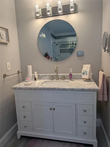 Totally renovated primary bath (2023) features vanity with marble sinktop, luxury vinyl, new mirror, light fixture and satin nickel hardware.flooring, mirror, light fixture, hardware and faucets.