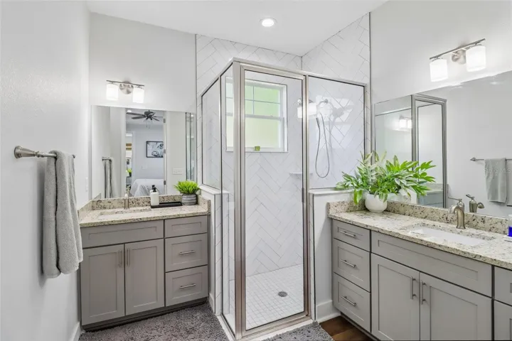 Primary bath with walk-in shower unit and double vanities and storage