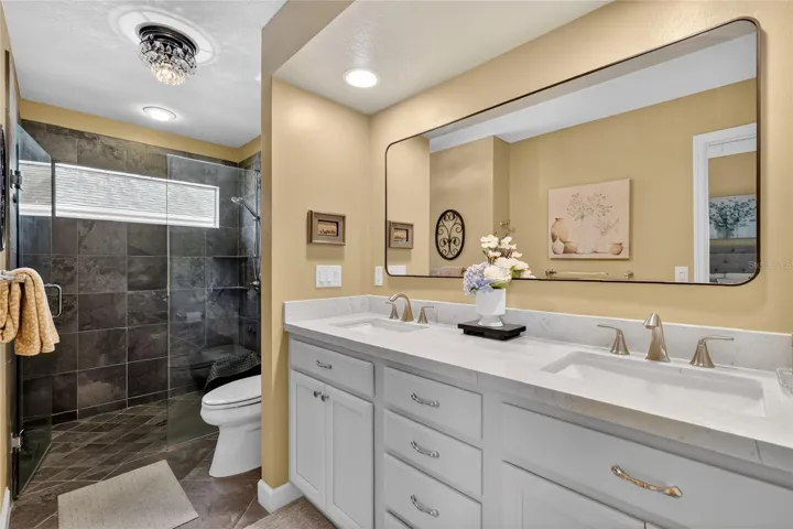 Primary en-suite bathroom with Carrera Marble topped dual sinks and roll in shower
