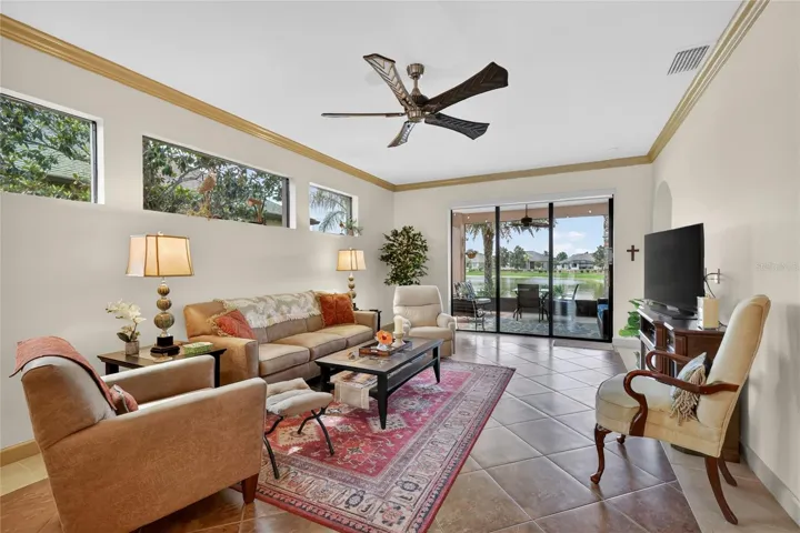 Living room with tile, crown molding, and triple sliders to the lanai and view!