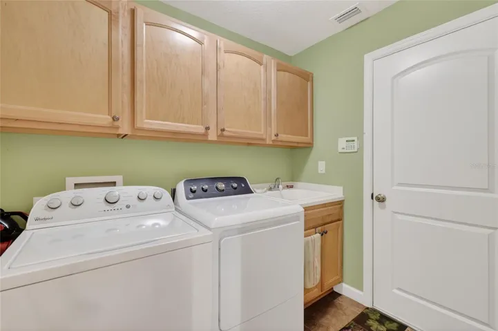 Laundry with tile, upper cabinetry and sink