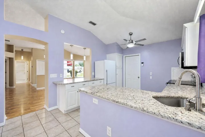 KITCHEN - Arched ENTRYWAY (L), PASS THRU WINDOW (Center), and access door to 2 CAR GARAGE (R). Note SimpliSafe Security System next to garage access door.