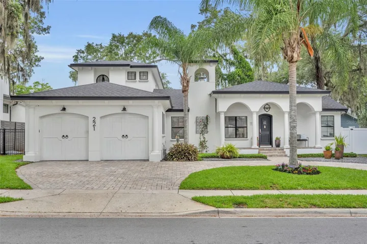Elegant Mediterranean-style home with a three-car garage, manicured landscaping, and a grand circular driveway.