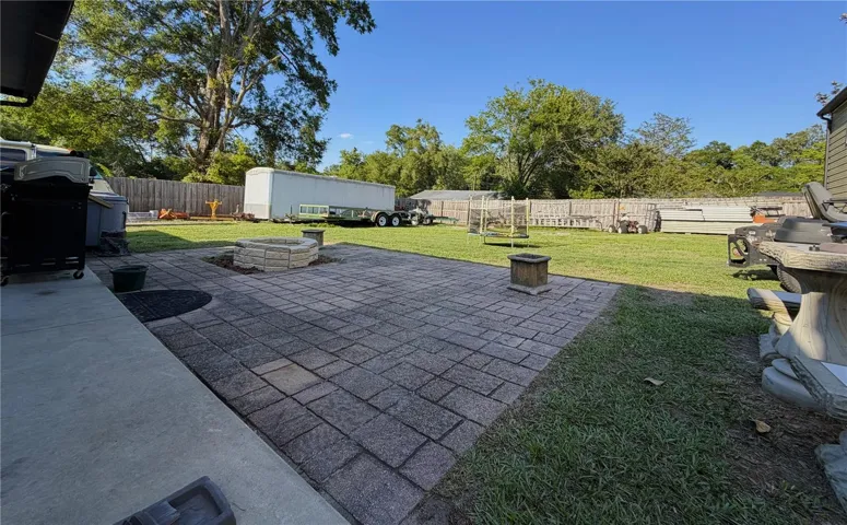 Concrete covered patio extends to an open brick paver area.
