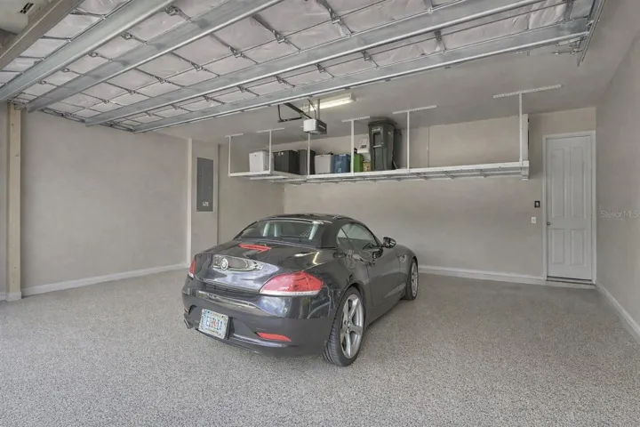 Spacious 2-car garage featuring a durable epoxy-coated floor and ample storage with suspended heavy-duty metal shelving racks.